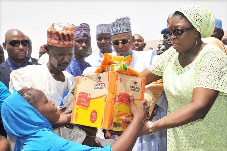 M.D. Dangote Foundation, Zouera Youssoufou, (Right)Presenting Food Items to one of The Beneficiary with his Farther(Left) While Borno State Governor (Middle) Alhaji Kashim Shettima, AtThe Distribution of Dangote Foundation Donate Foods Items for Ramadanto (IDP) Internal Displays People of Bakkasi Camp in Maiduguri BornoState. on 13-06-2016 